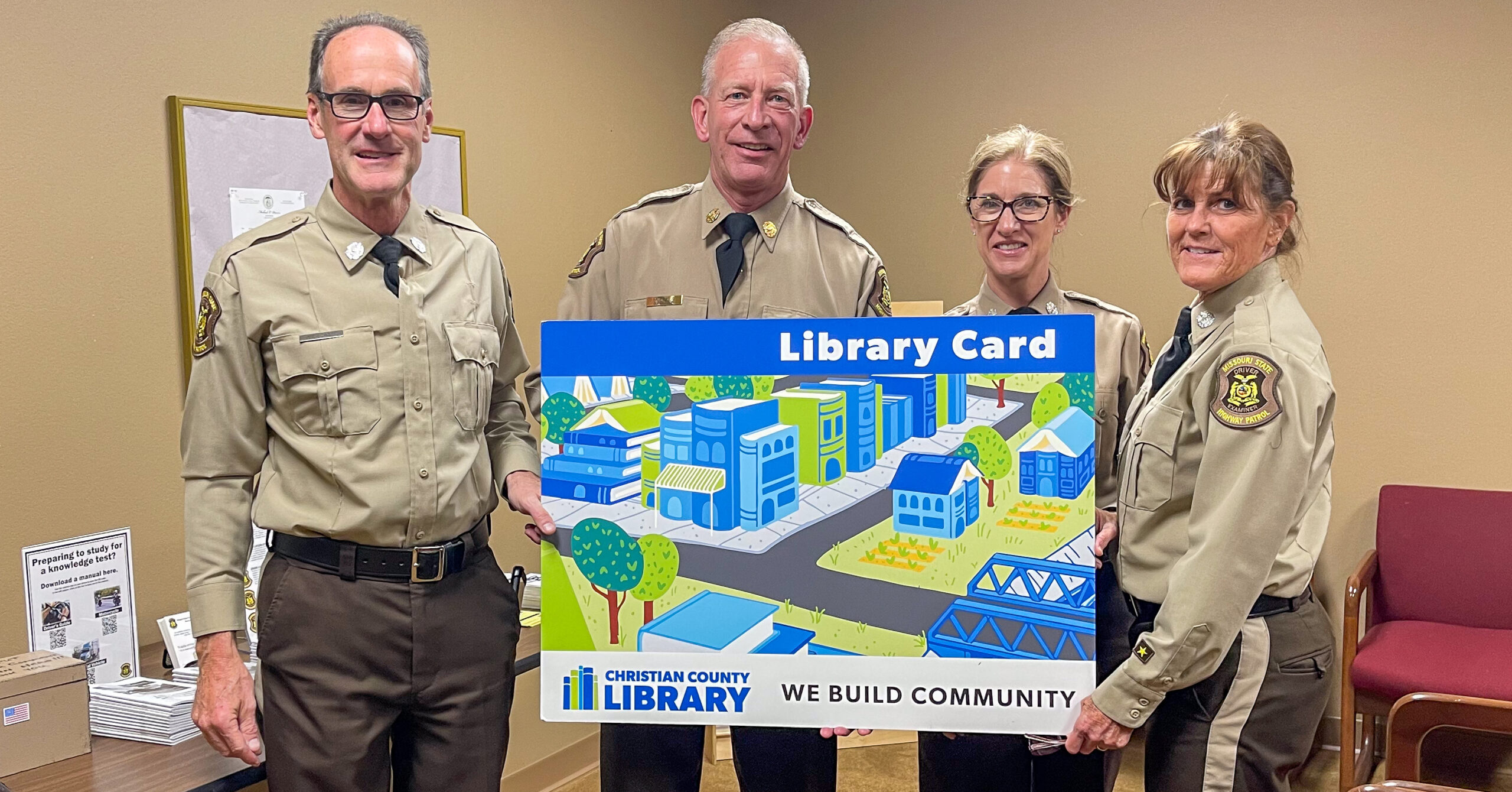 Four highway patrol officers hold an oversized Christian County Library card.