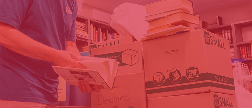 Photo of Friend of the Library President flipping through a book while sorting through boxes of book donations.